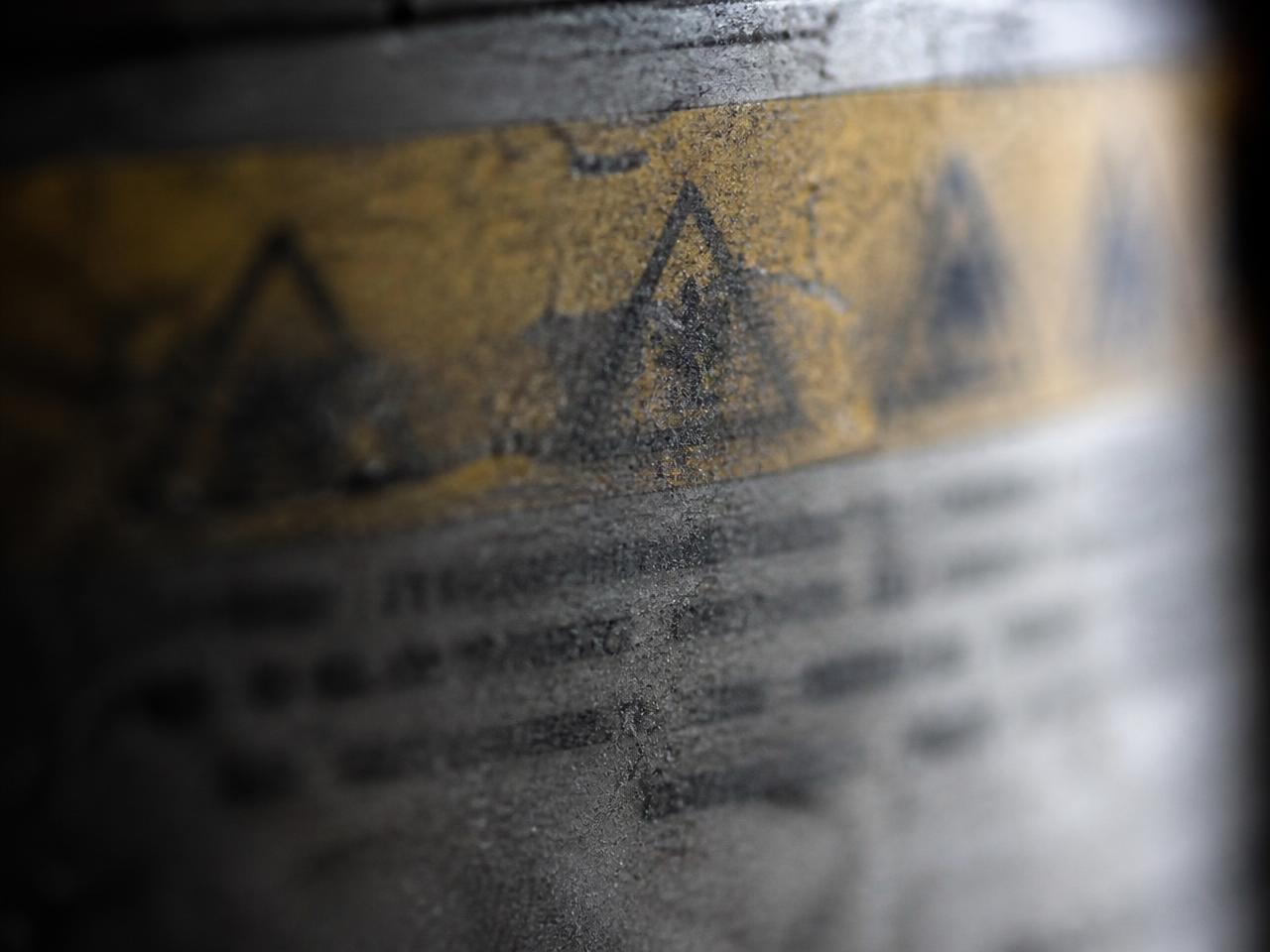 Extreme close-up of the scuffed warning-label area of a generic aerosol can, the printed text out of focus and unreadable